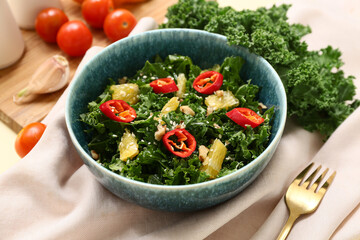 Bowl of tasty kale salad with chili pepper and orange on table