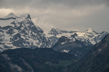 Majestic snow-covered mountains rise under a cloudy sky in a remote alpine region during early morning light