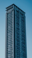 Fototapeta premium Modern high-rise building against clear blue sky capturing urban architecture