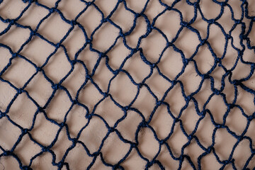 A close-up of a fishing net, showcasing its intricate weave and maritime texture, perfect for nautical and coastal themes.