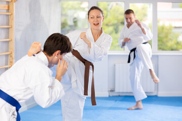 Woman and man in kimono sparring together in gym during karate training