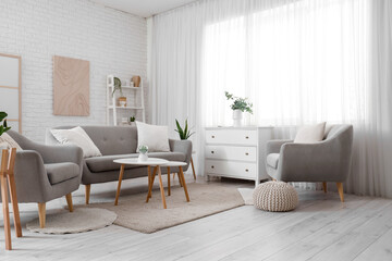 Interior of light living room with curtain, sofa and armchairs