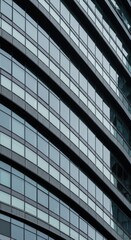 Obraz premium Curved glass facade of modern office building reflecting urban landscape