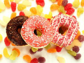 Pink and chocolate donuts on colorful sweet candy jelly. High level of sugar products. Popular international sweets.