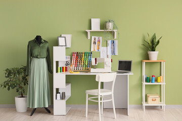 Tailor's workplace and mannequin near green wall in atelier