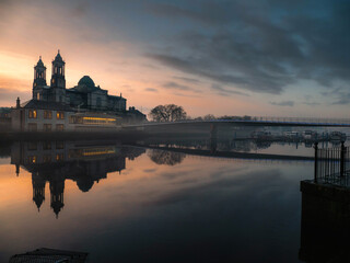 View on Church of Saints Peter and Paul at dusk. Warm color light. Cloudy sky reflects in river...