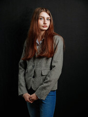Young business woman in grey suit posing on dark background. Fashion and style concept. Model has...