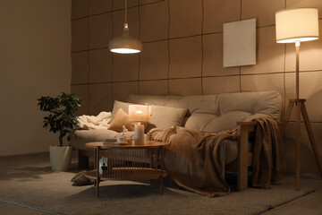 Interior of living room with sofa, table and glowing lamps in evening