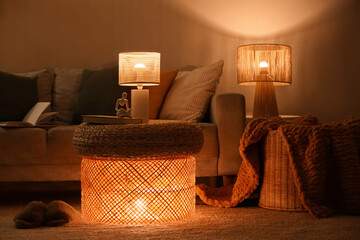 Interior of dark living room with sofa and glowing lamps at night