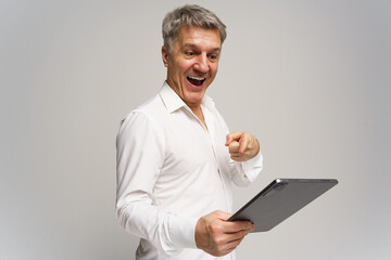 Excited man engaging with a tablet in a studio during a cheerful moment of discovery