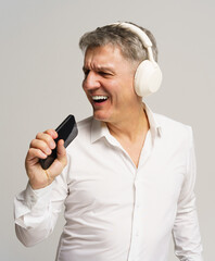 Man enjoying music while singing with a smartphone in his hand in a bright indoor setting