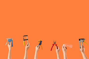 Many hands with construction tools on orange background
