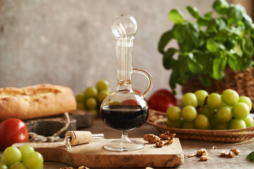 A bottle of Italian balsamic vinegar with tomatoes, ciabatta, basil, grapes and nuts