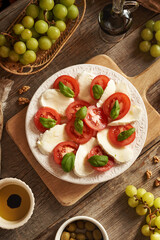 Fresh tomatoes, mozzarella cheese and basil in Italian Caprese salad, with balsamic vinegar, olive oil and walnuts