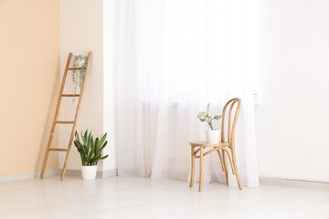 Ladder with chair and plants near light curtain in room