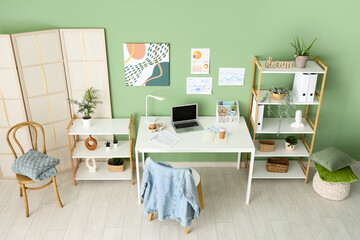 Interior of modern office with workplace, shelf units and folding screen