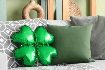 Clover made of balloon with cushions on sofa in living room decorated for St. Patrick's Day, closeup