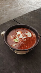 Czech goulash soup with onion on wooden table by vltava river in cesky krumlov