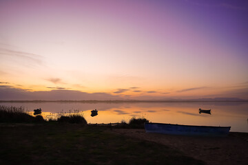 Small wooden rowing boat on a calm lake at sunset reed in France