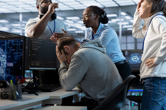 Employees berating engineer in office after mistake leading to errors in high tech AI data center. IT workers scolding admin in server farm after damaging artificial intelligence supercomputers