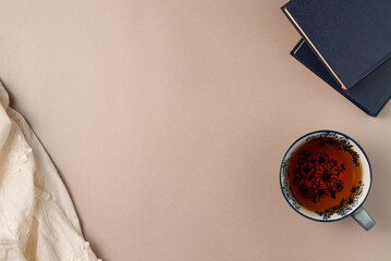 Books with cup of tea on beige background from above. Flat lay, top view. Copy space