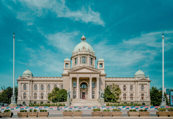 Stunning view of an ornate neoclassical building under a clear blue sky. The architecture features a central dome, symmetrical wings, and detailed sculptures that adorn the facade. 