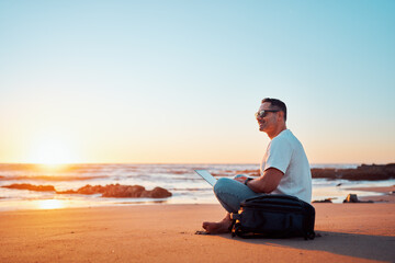 Fototapeta premium Freelancer enjoying working on the beach at sunset