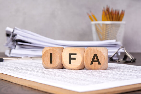 wooden blocks spelling 'IFA' on financial documents, symbolizing investment and financial advisory services