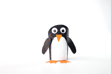 a craft representation of a penguin made from recycled toilet paper roll. painted with a black body and a white belly. round eyes. for art and craft projects
