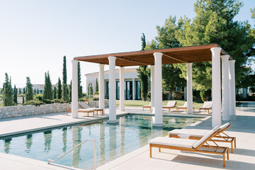 Canopy with columns over a long swimming pool with sun loungers. Hotel Amanzoe, Peloponnese, Greece