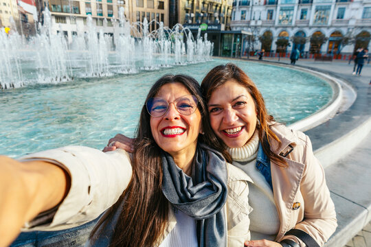 Two smiling mature women taking a selfie in spanishc ity
