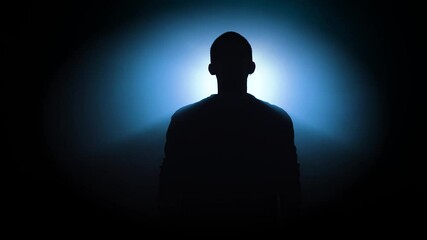 A striking and dramatic silhouette of an individual is beautifully illuminated by a mysterious blue light effect