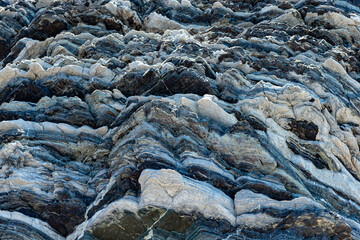 Compressed rock layers formation in various colors and thicknesses, on south central coast of the...