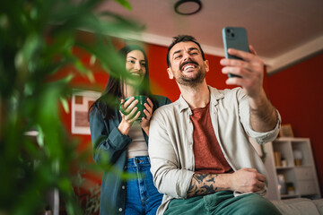 couple smiling and pose while take self portrait on mobile phone
