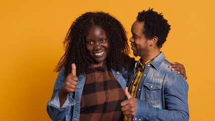 Affectionate husband and wife giving a like symbol on camera, african american couple posing with...
