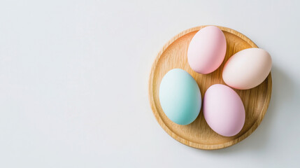 Pastel colored eggs on wooden plate against white background