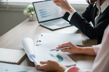 Business professionals reviewing financial charts and graphs in an office environment, focusing on data analysis and teamwork.