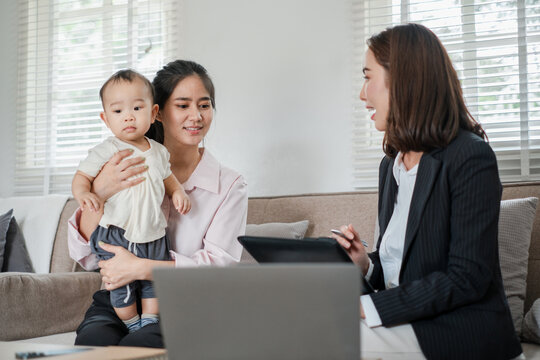 Businesswoman consulting with a mother holding her baby in a modern home office environment. - Powered by Adobe