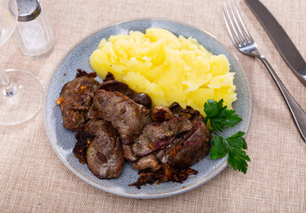 Restaurant serves puree potatoes with large bits of fried chicken liver and onion as main course. Dish decorated with parsley leaf