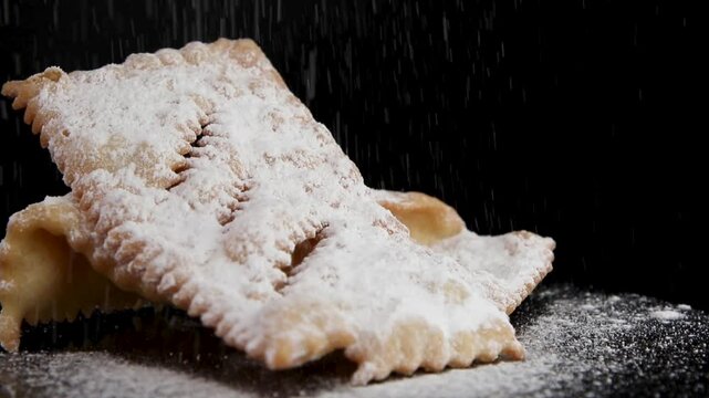 A 360-degree view of crispy Dolci di Carnevale called chiacchiere, with powdered sugar sprinkled on top, set against a black background. Traditional Italian carnival sweets, perfect for food content.
