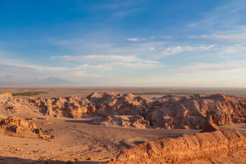 Moon valley famous desert landscape in Chile. Atacama desert tourist sight Valle de la Luna with stunning dry soil arid landscape of red rocks and sand under blue sky  on Altiplano high altitude plain