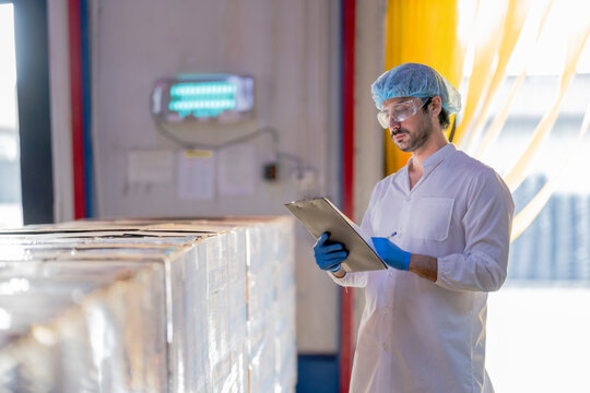 A supervisor in a food processing plant wearing protective gear, inspecting a fish while holding a clipboard, emphasizing quality control, hygiene, and safety in the seafood production process.