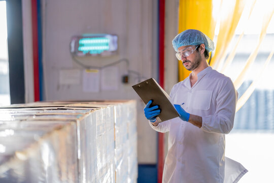 A supervisor in a food processing plant wearing protective gear, inspecting a fish while holding a clipboard, emphasizing quality control, hygiene, and safety in the seafood production process. - Powered by Adobe