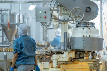 Industrial food production line with a worker ensuring process accuracy and safety Focus on automated systems precision and manufacturing hygiene.