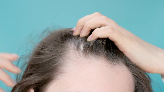 Woman touching her hair close-up on mint background, hair loss concept.