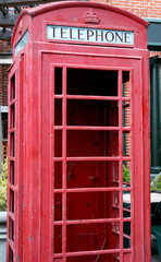 Obraz premium A classic red British telephone booth outdoors in London showcases historic architecture and urban charm.