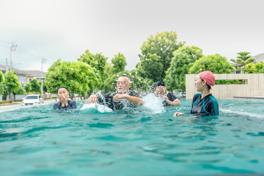 people enjoys a fun water activity in a swimming pool, playing a ball game with smiles and laughter. The scene emphasizes health, active living, and social engagement in an outdoor environment.