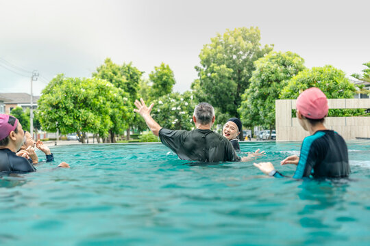 people enjoys a fun water activity in a swimming pool, playing a ball game with smiles and laughter. The scene emphasizes health, active living, and social engagement in an outdoor environment.