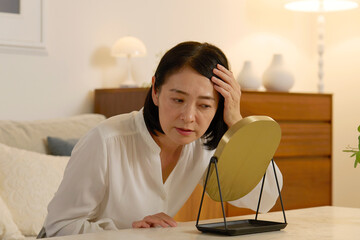 髪の毛の悩みがある50代の女性　夜のリビング