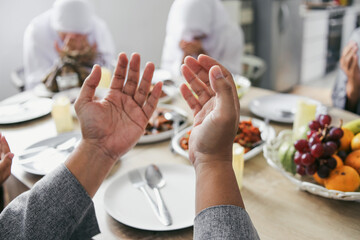 Fototapeta premium Portrait of Raised Hands Praying Before Eating Together With Family On Eid Al Fitr Celebration